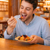 Homme qui mange des pancakes dans une assiette en palmier