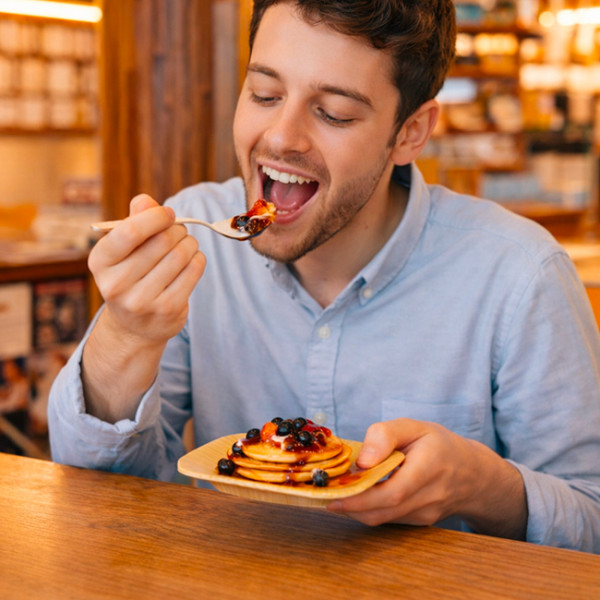Homme qui mange des pancakes dans une assiette en palmier