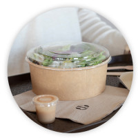 Boite a salade en carton avec couvercle en plastique sur un plateau de restaurant