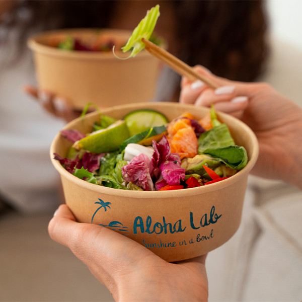 Salade emportée, mangée dans des boîtes rondes en carton personnalisées avec baguette