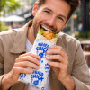 Homme qui mange wrap emballer dans un papier ingraissable personnalisé de fastfood
