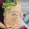 Sac kraft personnalisé rempli de légumes et vendu sur un marché par un primeur