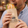 Homme qui mange un sandwich avec un sachet personnalisé d'une boulangerie